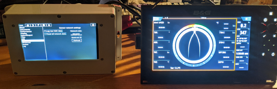 The electronic device sits on a desk, powered on, next to the multi-function display. Both are connected to the same NMEA2000 bus.