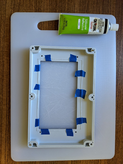 A gasket is taped inside the lid while the adhesive cures
