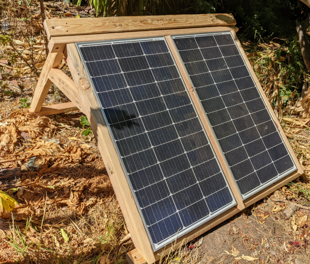 A wooden 45-degree A-frame with two solar panels mounted facing out from one side