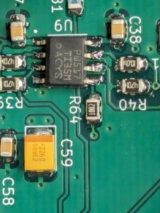 Close-up of a section of a PCB with an IC and some capacitors. The IC pins are misaligned relative to the pads.