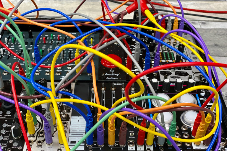 Some Eurorack modules connected to one another by a rainbow spider web of patch cables