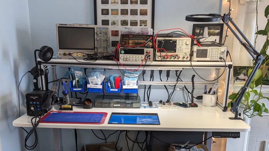 A standing desk with a shelf mounted on top with an aluminum bracket.